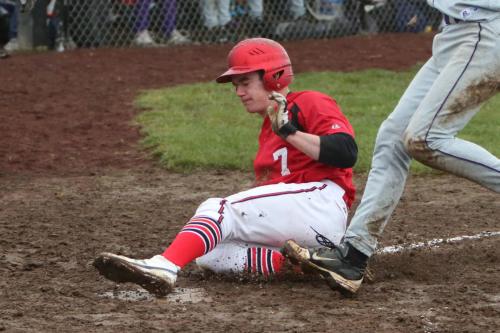 Jake Tumblin slides into the mud pit that home plate became Saturday afternoon. (John Fisken photo)