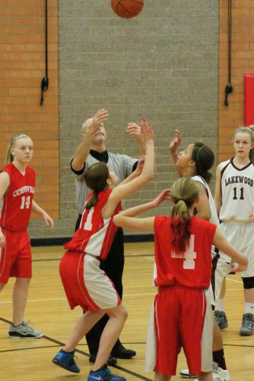 Katrina McGranahan (in red) prepares for the opening tip in a 7th grade varsity game. Watching her are teammates Sage Renninger (14) and Payton Aparicio (4).